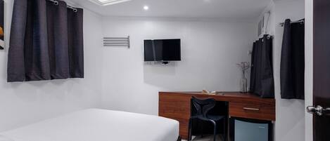 Un dormitorio con cama, escritorio y televisor.