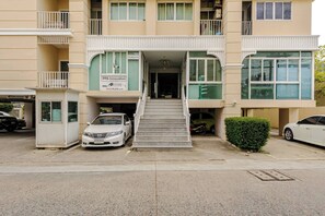 A multi-story building with a central entrance, a staircase leading to the ground floor, and a car parked in front. - 1 BR 5 Mins BTS Bearing 7-11 and Lotus (Samut Prakan)