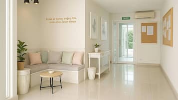 A clean, modern hallway with a seating area, a trash bin, and a bulletin board.