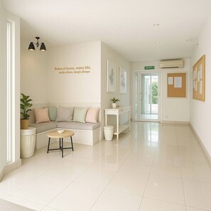 A clean, modern hallway with a seating area, a trash bin, and a bulletin board.