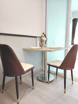 A modern room with a round table, two chairs, a vase with flowers, and a book on the wall. - 1 BR 5 Mins BTS Bearing 7-11 and Lotus (Samut Prakan)