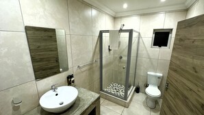 Un baño con lavamanos, inodoro y ducha con mampara de vidrio.