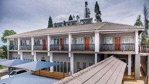 Un hotel de varios pisos con techo de tejas, balcones y un espacio al aire libre cubierto con sombrillas.