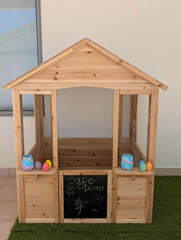 A wooden playhouse with a chalkboard sign reading 'Ogre Disco' and colorful balls on shelves.