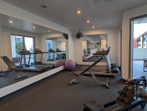 Une salle de sport équipée de tapis de course, de ballons d’exercice et d’un appareil d’aviron.