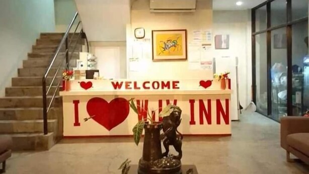 A reception desk with a 'WELCOME' sign and a heart symbol. There is a staircase to the left and a statue in the center. - WJV INN CASUNTINGAN (Mandaue)