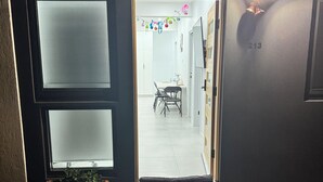 Une porte qui mène à une pièce comprenant un coin repas, une plante en pot et le numéro « 213 » peint sur le mur.