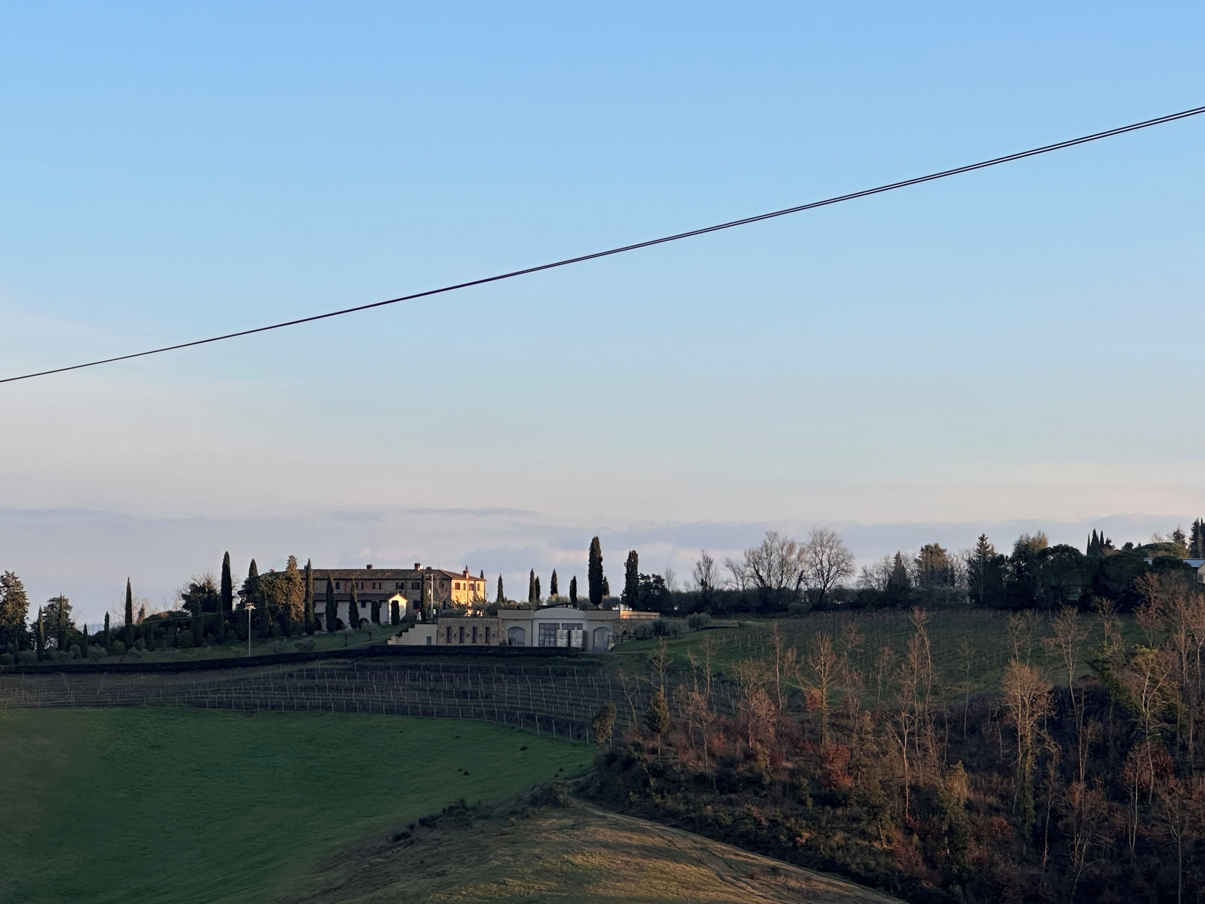 A rural landscape with a large building, possibly a hotel, surrounded by trees and fields.