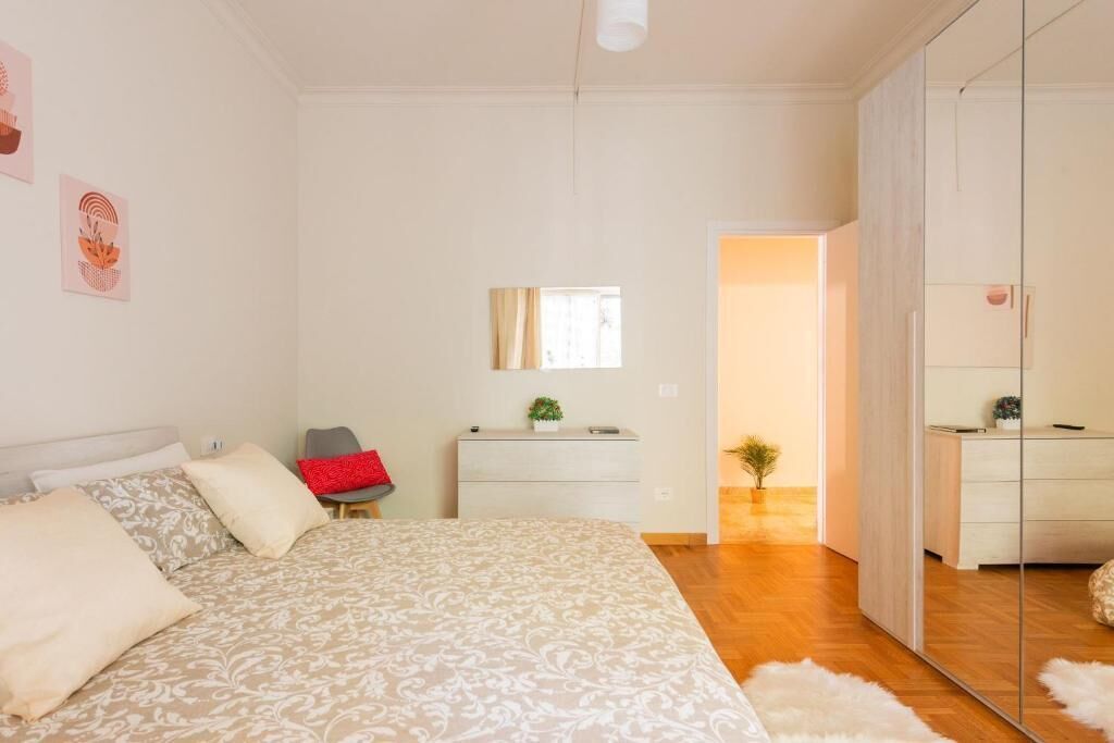 A bedroom with a bed, a dresser, a mirror, and a small plant.