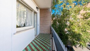 A balcony with a patterned floor, a window with curtains, and a tree in the background. - MaSa Holidays House Vatican (Roma)