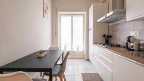 A modern kitchen with a dining area, featuring a black table, grey chairs, and a view through a glass door. - MaSa Holidays House Vatican (Roma)