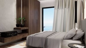 Ein modernes Schlafzimmer mit Bett, Nachttisch, Koffer, Topfpflanze und Meerblick.