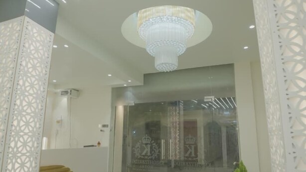 A modern hotel lobby with a marble floor, a chandelier, and patterned walls. - Knightz bridge (Faizabad)