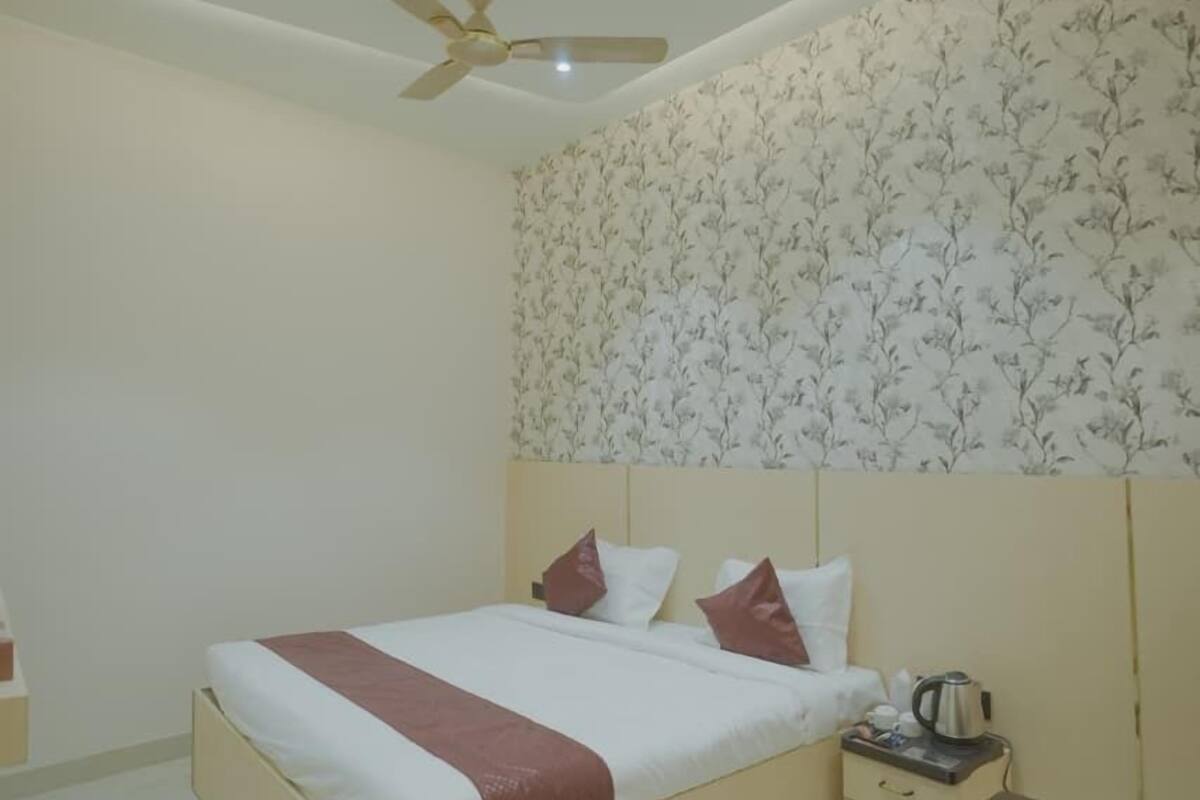 A bedroom with a bed, a ceiling fan, recessed lighting, a nightstand, and a glass-top table.