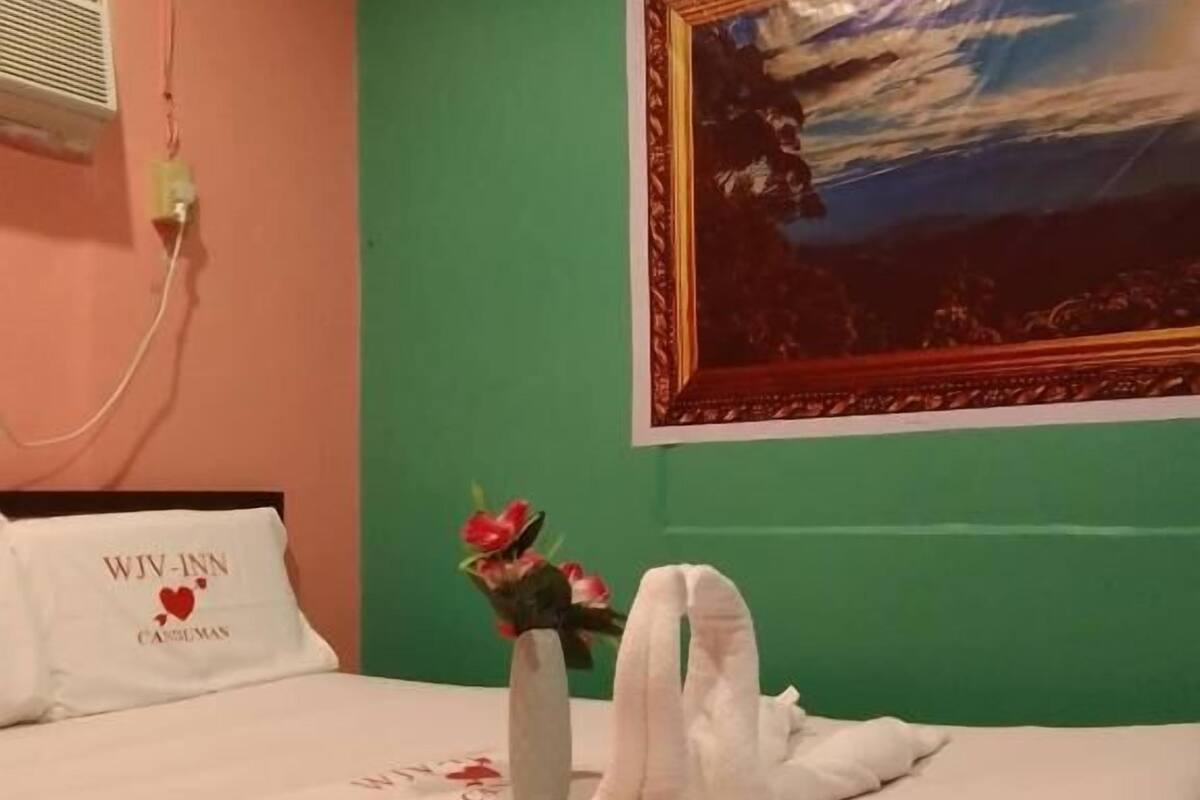 Una habitación de hotel con una cama, un cuadro y un ramo de flores.