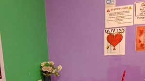 A small room with a white table and two red chairs. There are several signs on the wall, including one that says "WAV INN" and another with a heart symbol. A vase with flowers is on the table. - WJV INN CANDUMAN (Mandaue)