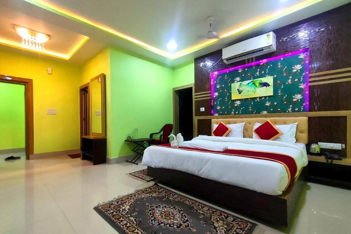 Una habitación de hotel con una cama grande, un aire acondicionado de pared, una lámpara en el techo y un adorno floral en la pared.