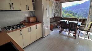Eine Küche mit Holzausstattung, einem Kühlschrank, einem Herd und einem Essbereich mit Stühlen und einem Tisch.