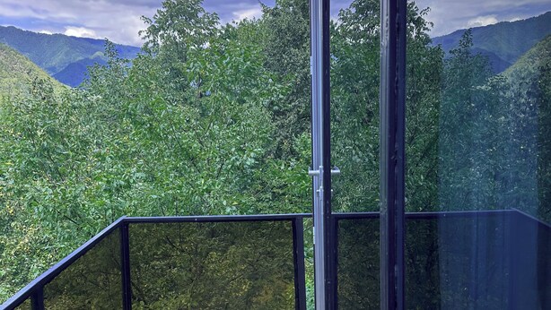 Eine Holterrasse mit Glasgeländern mit Blick auf eine gebirgige Landschaft.