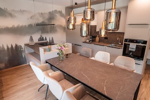 A modern kitchen with a large island, pendant lighting, and a scenic wall mural. - Vacation apartment Tenne with whirlpool 90 sqm, 2 bedrooms up to max. 4 persons (Samerberg)