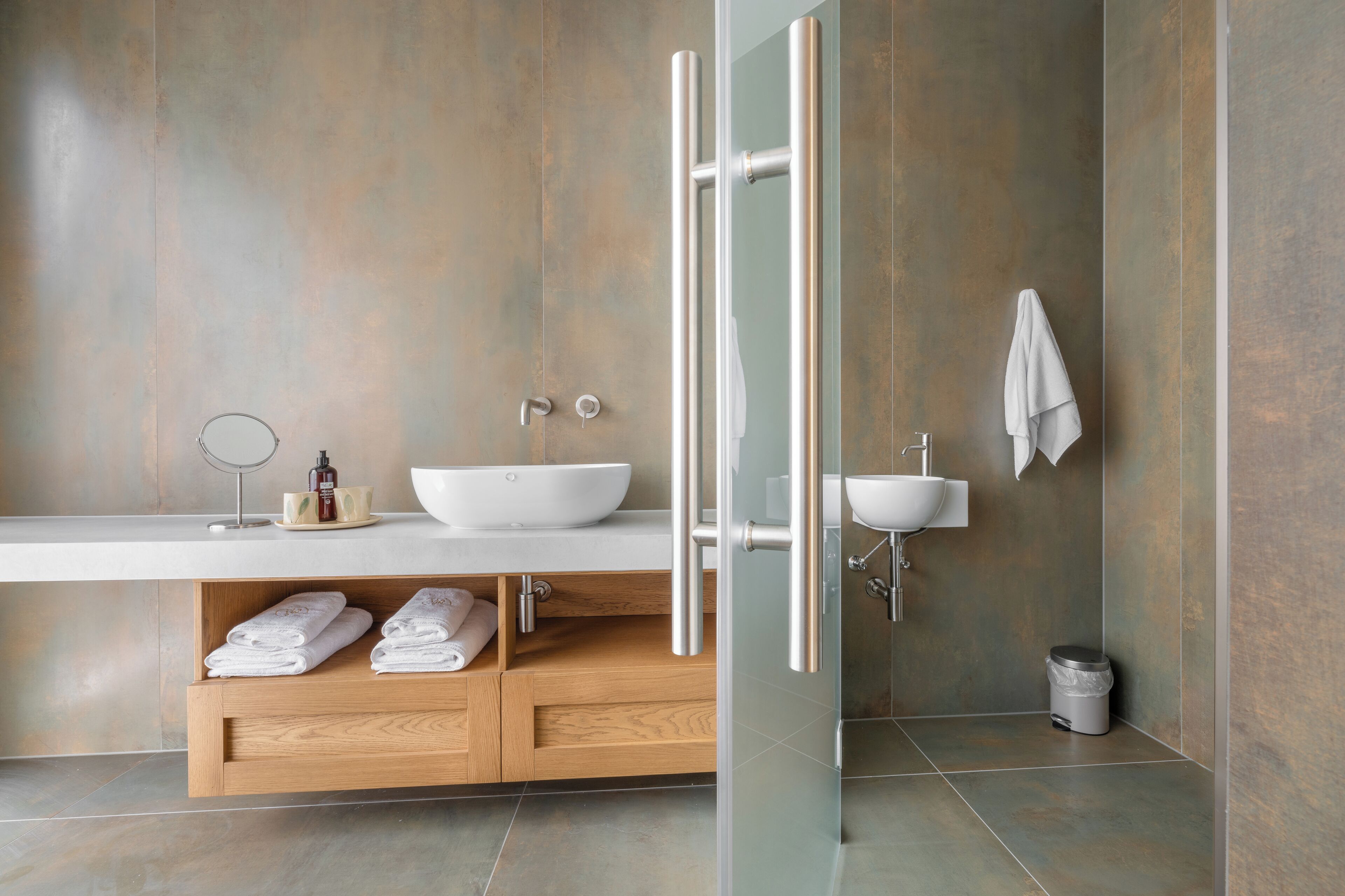 A modern bathroom with a large white sink, a mirror, and a glass-enclosed shower.