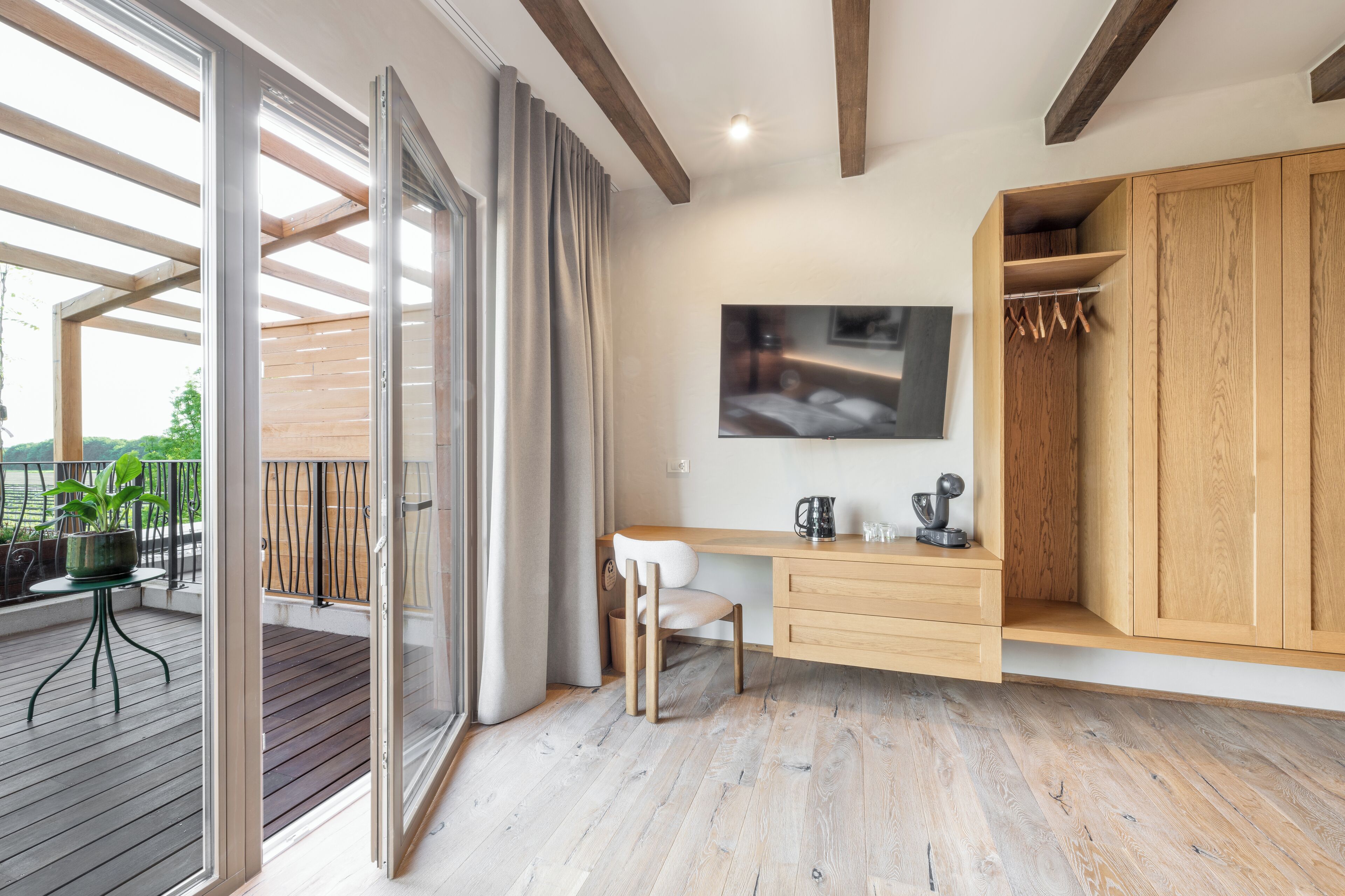 Quarto moderno com escrivaninha de madeira, uma cadeira, televisão fixada na parede e guarda-roupa de madeira.