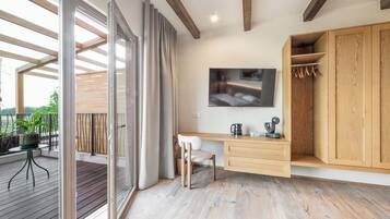 Quarto moderno com escrivaninha de madeira, uma cadeira, televisão fixada na parede e guarda-roupa de madeira.
