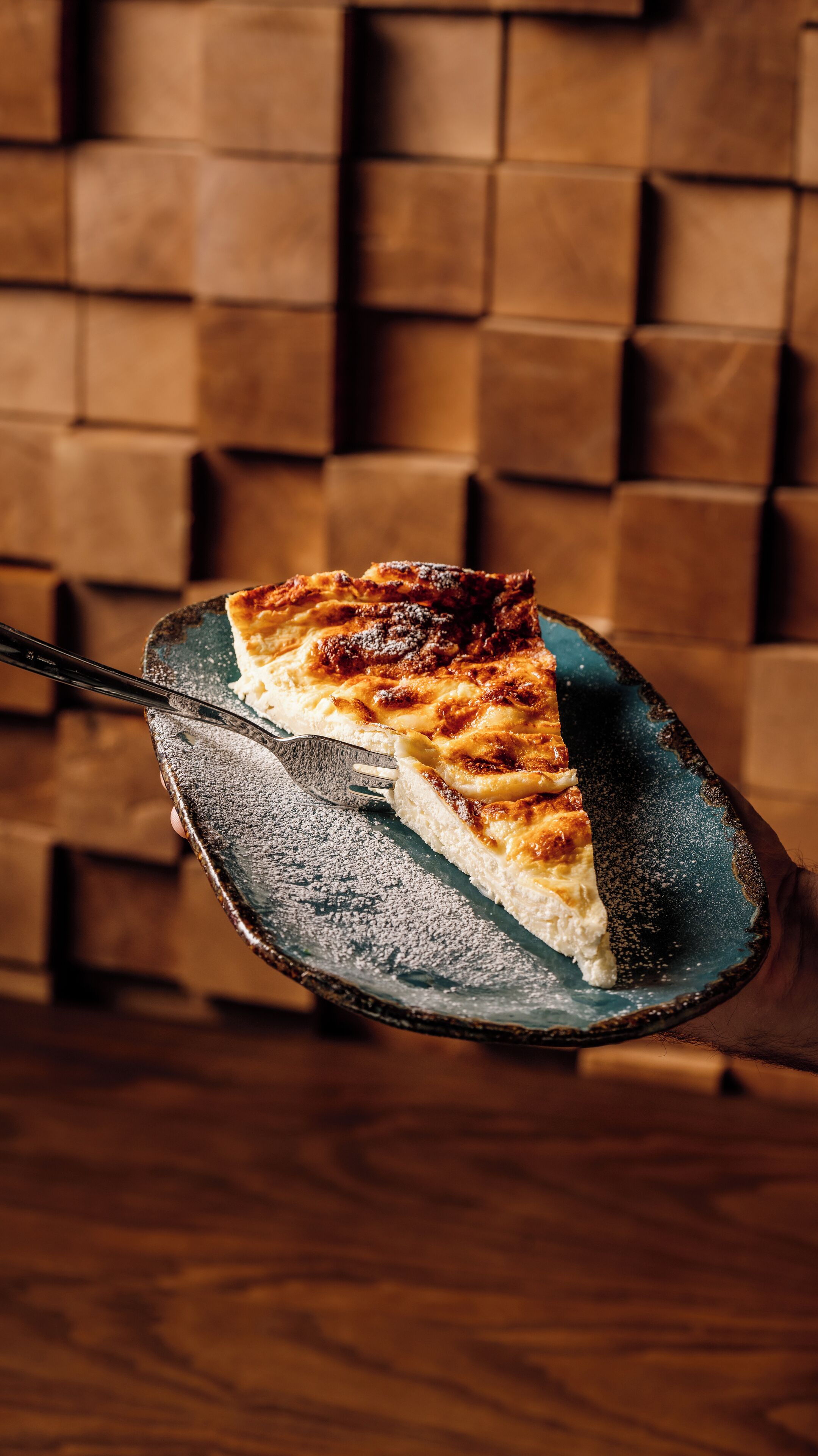Una porción de tarta sobre un plato de cerámica con un fondo de madera.