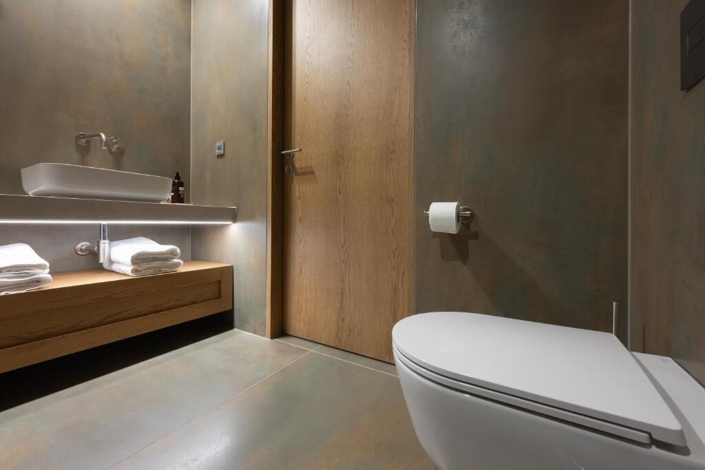 A modern bathroom with a wooden vanity, a white sink, and a toilet.