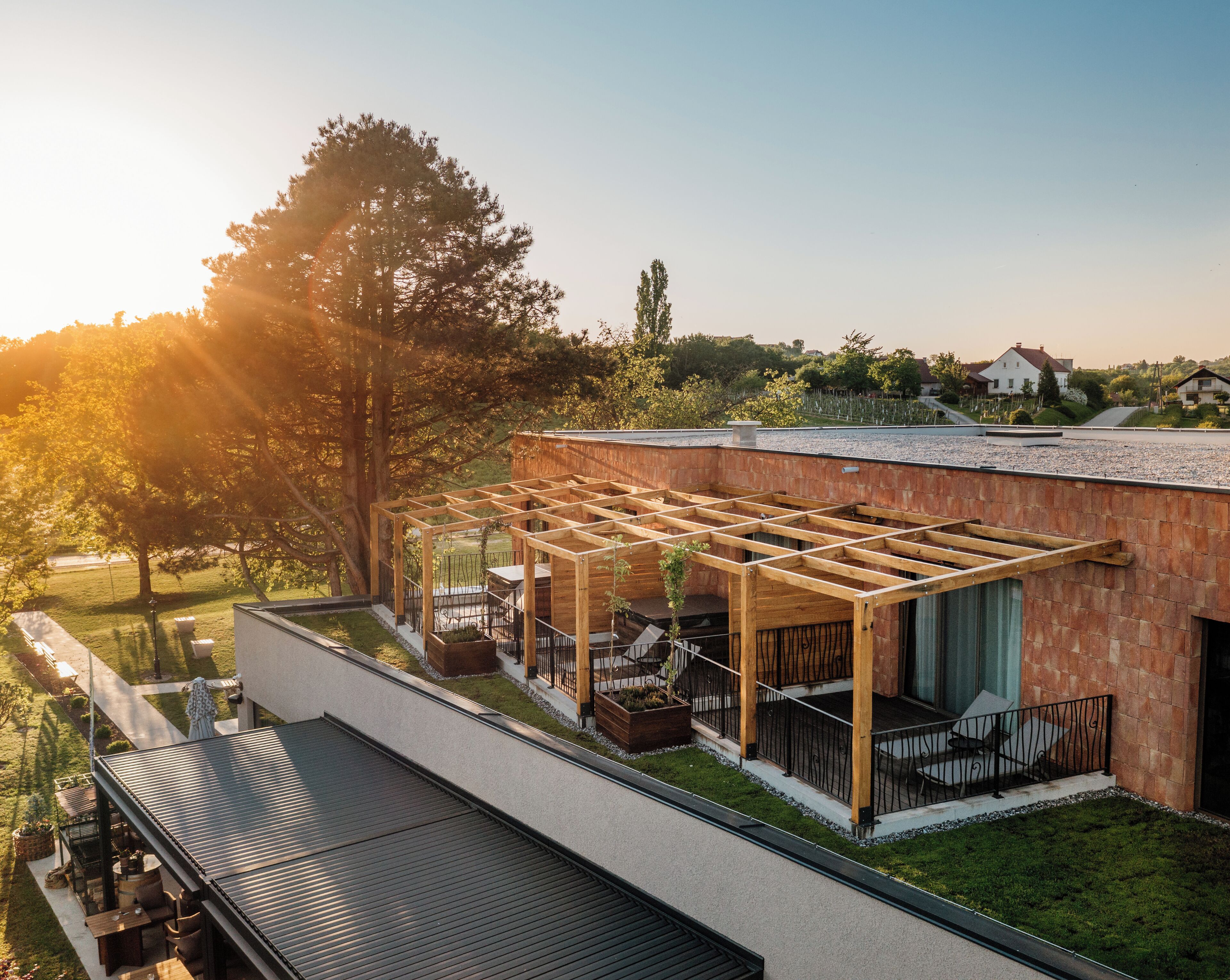 Een modern huis met een houten pergola, een terras met tuinmeubilair en uitzicht op het omliggende landschap.