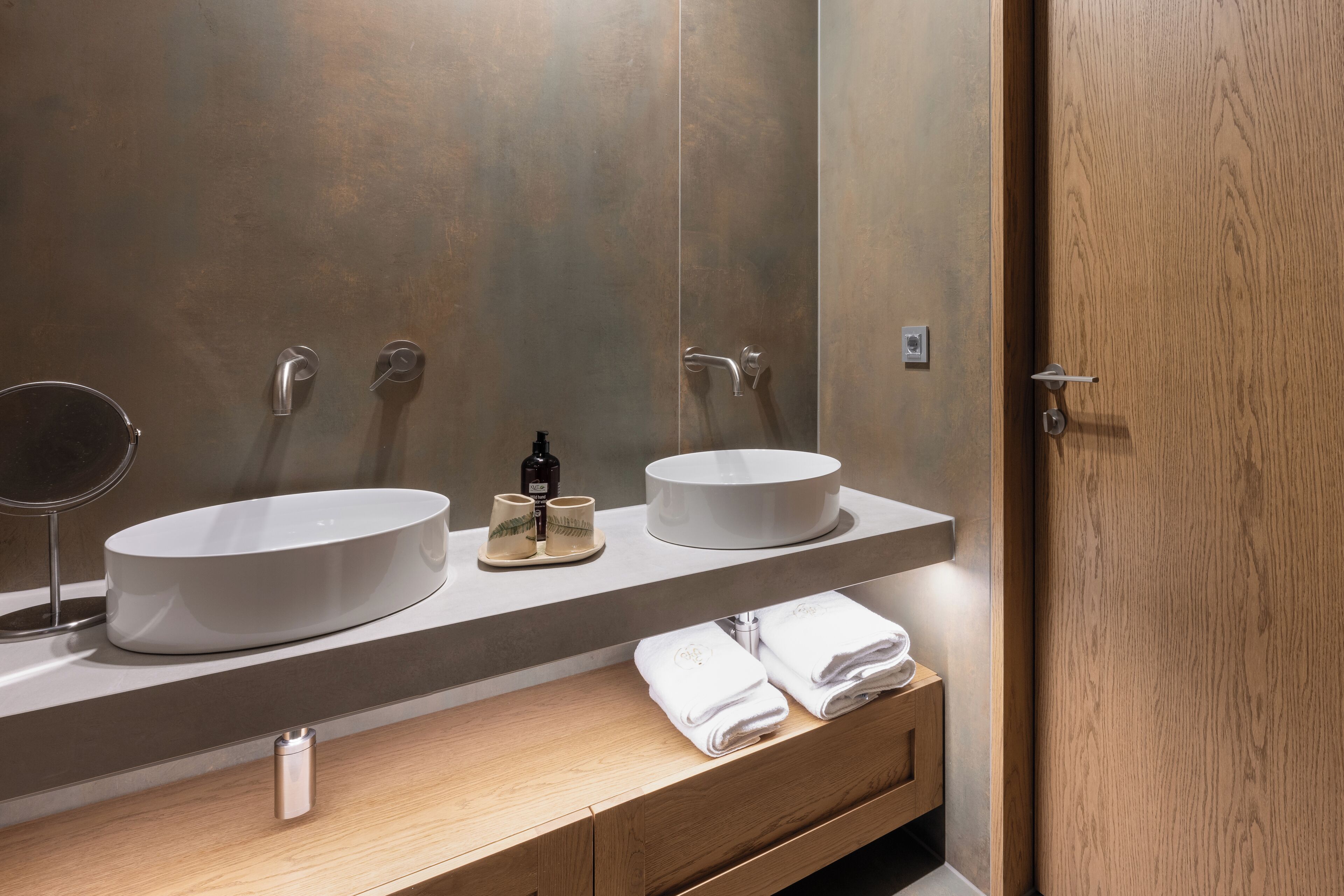 A modern bathroom with two sinks, a mirror, and a wooden vanity.