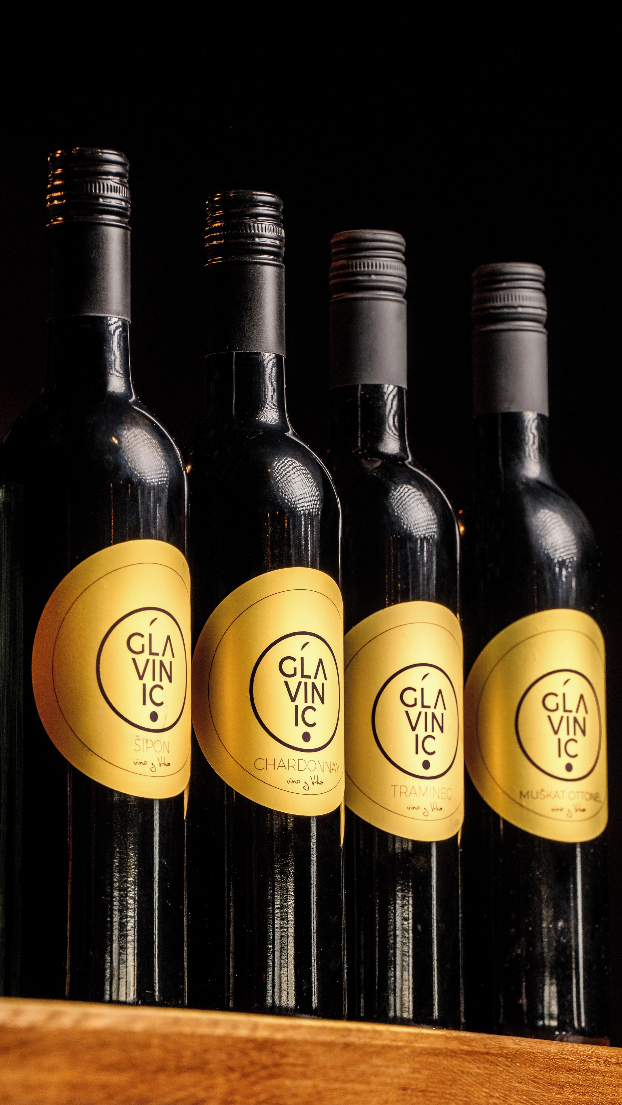 Four bottles of wine with labels, arranged in a row.