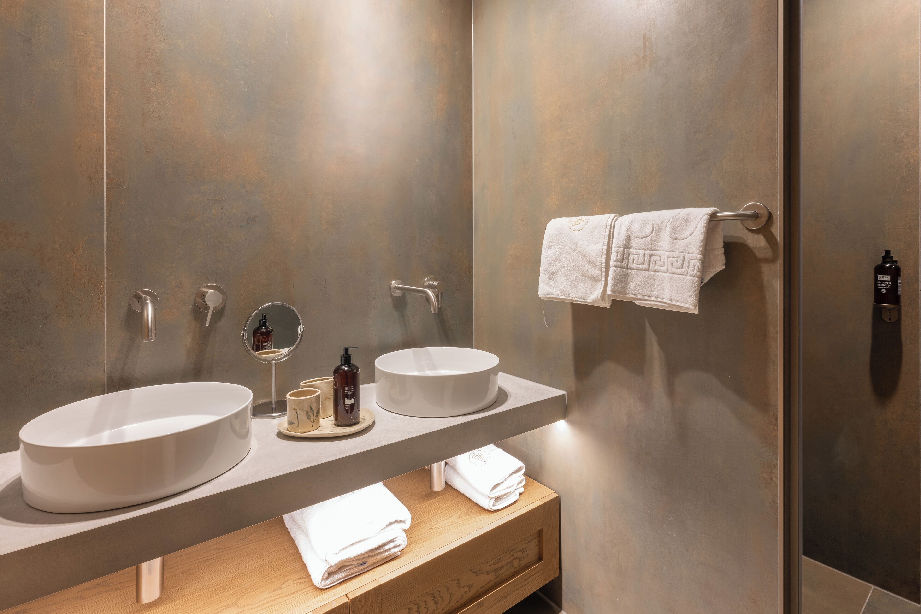 Un baño moderno con dos lavamanos amplios, un espejo y un perchero para toallas.