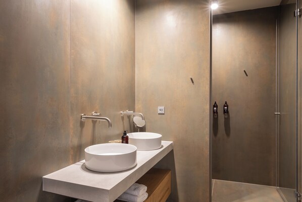 A modern bathroom with two round sinks, a mirror, and a shower.