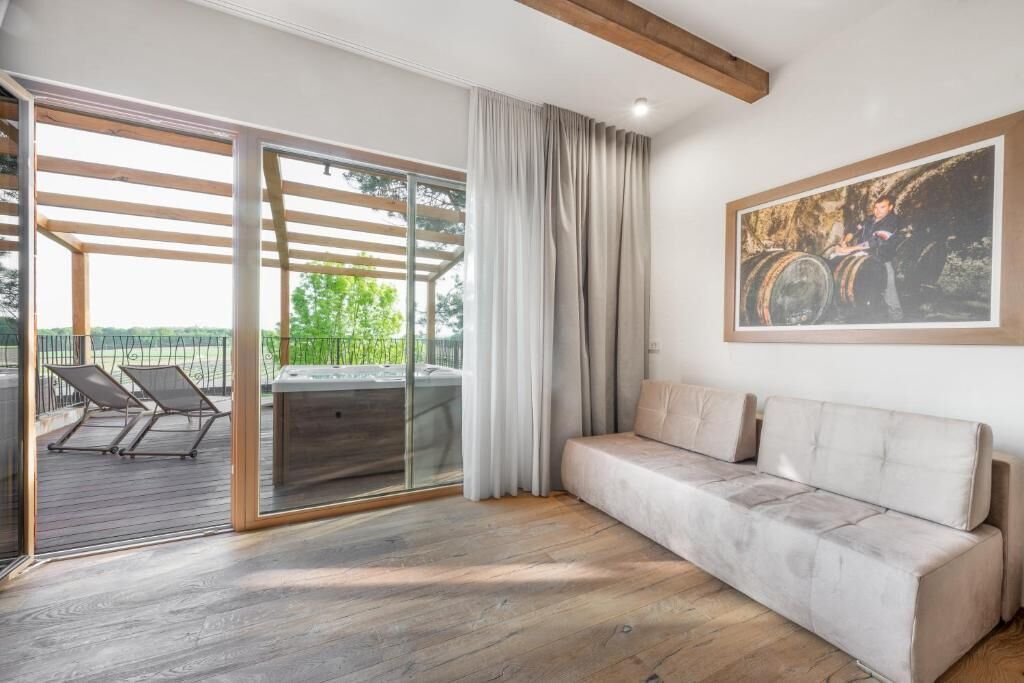 A modern living room with a sofa, a glass door leading to an outdoor area, and a painting on the wall.