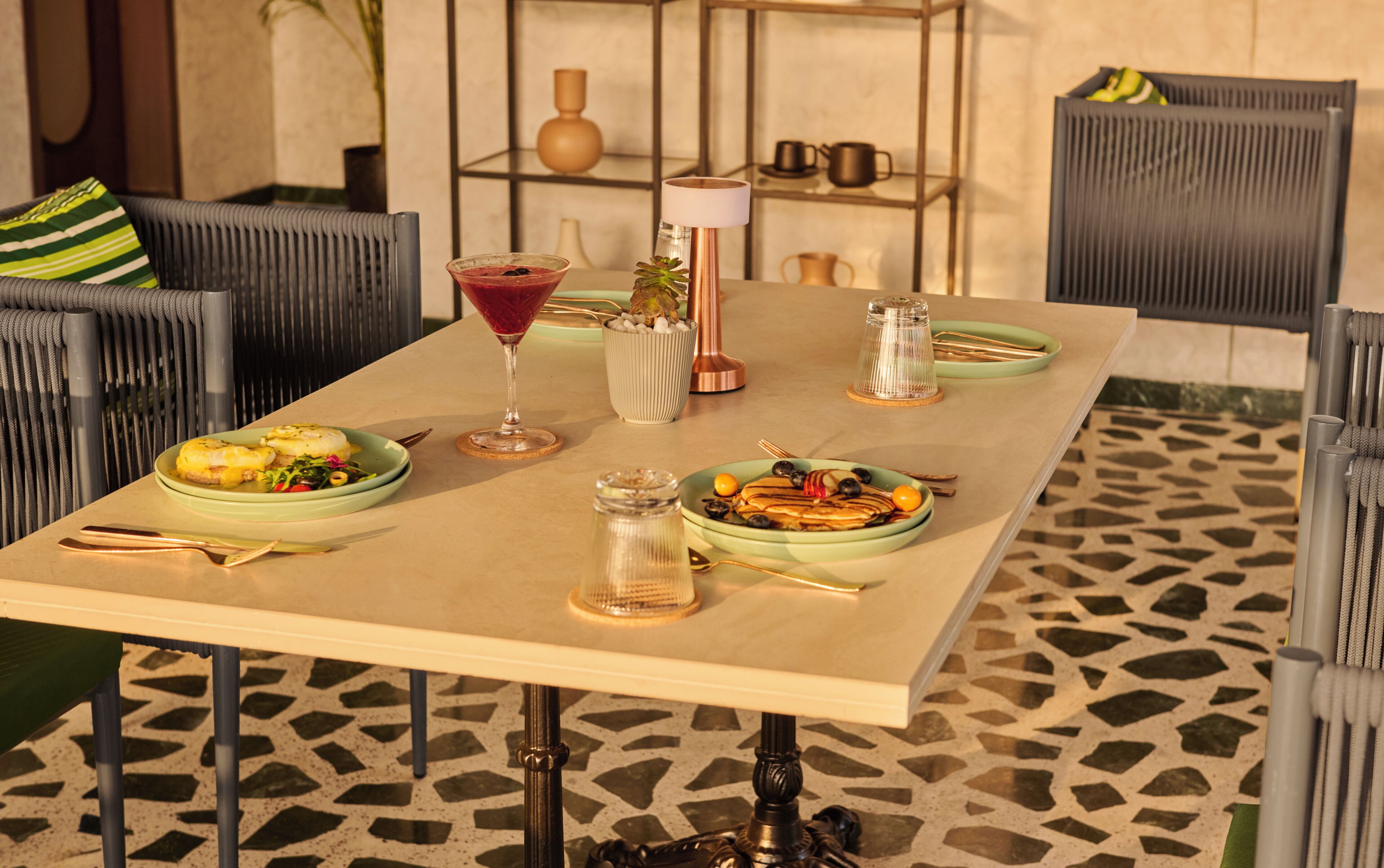 Una mesa de comedor con platos de comida, una copa de martini y una vela.