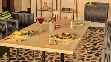 Una mesa de comedor con platos de comida, una copa de martini y una vela.