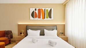 A hotel room with a bed, a nightstand, a chair, a wall art piece, and a window with curtains. - Minimaist - Varanasi City Centre (Varanasi)