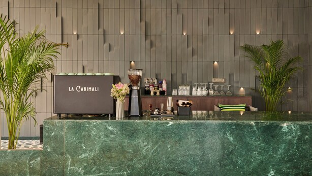 A reception desk with a marble counter, a coffee machine, and a wall-mounted light fixture. - Minimaist - Varanasi City Centre (Varanasi)