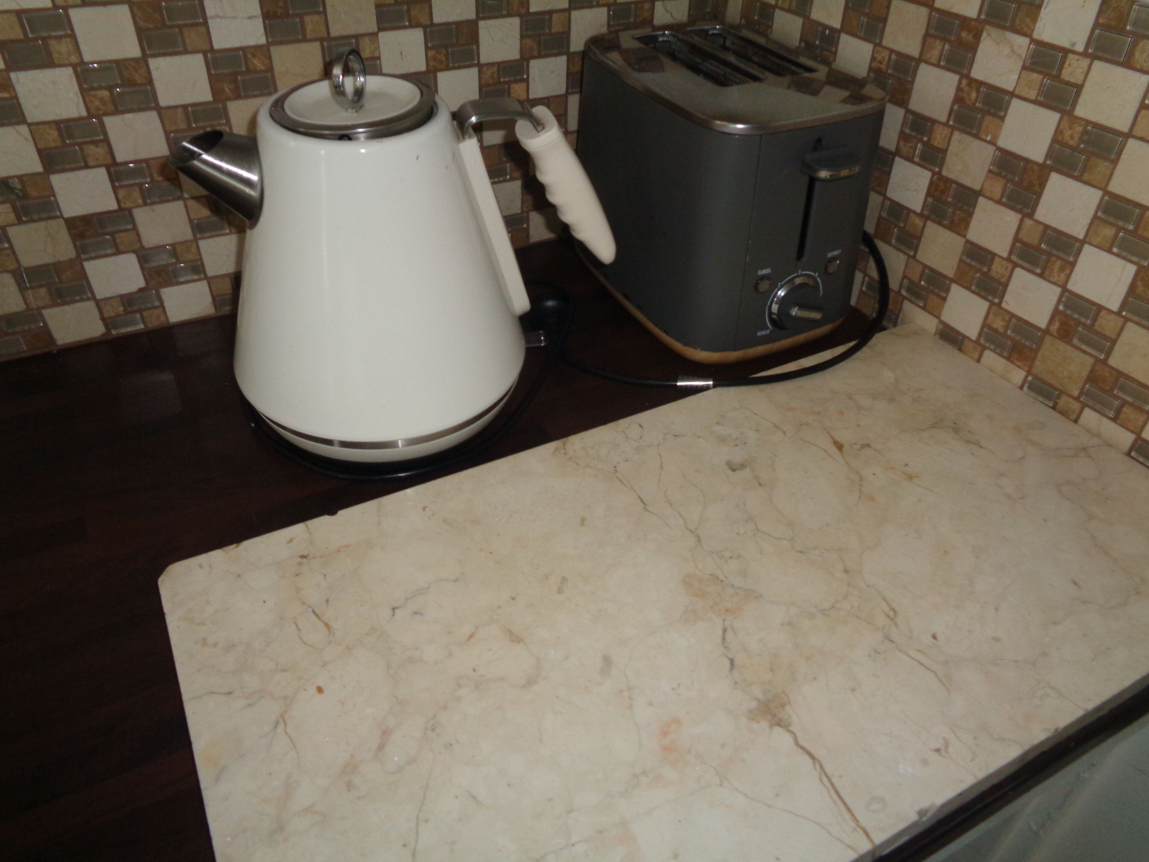 Una cucina con macchina del caffè, tostapane e pannelli di piastrelle.