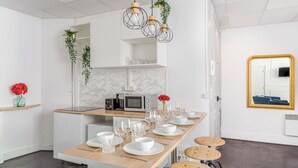 A modern kitchen with a marble backsplash, a built-in microwave, and a wooden island with bar stools. - Merveil Family Suite - Sebastopol III (Paris)