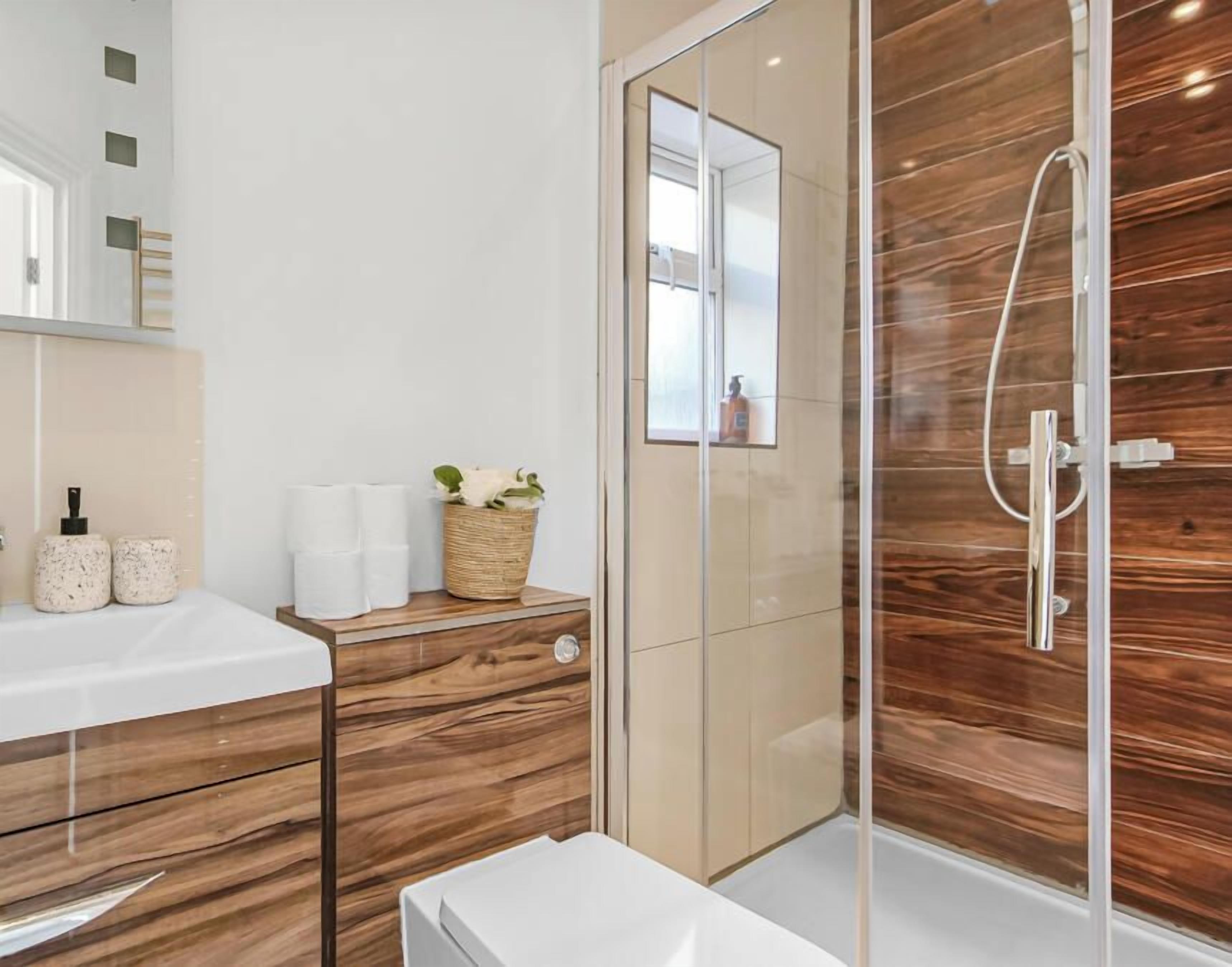 Ein modernes Badezimmer mit Duschkabine aus Glas, einem Holzwaschtisch und einem Spiegel.