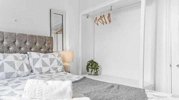 A neatly arranged bedroom with a tufted headboard, a patterned bedspread, two bedside lamps, and a bedside plant. - Exclusive 2 Bedroom Flat near Loughborough Junction! (Greater London)