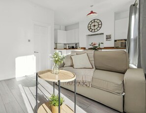 A modern living room with a sofa, a small round table, and a potted plant.