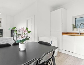 A modern kitchen with white cabinets, a black countertop, and a red pendant light.