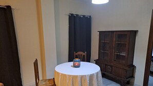 A small dining area with a round table, a chair, a cabinet, and a curtain. - Charming apartment for couples - discover magical Seville! (Tomares)
