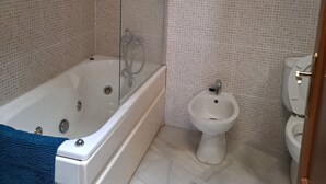 A bathroom with a bathtub, a shower, a bidet, and a toilet. - Charming apartment for couples - discover magical Seville! (Tomares)