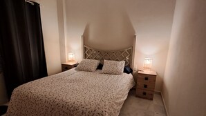 A bedroom with a bed, two bedside tables, a hanging light fixture, and a window with curtains. - Charming apartment for couples - discover magical Seville! (Tomares)
