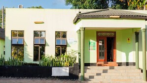 A building with a green facade, a tiled roof, and a front entrance with steps leading up to it. - Royal Shalom Lodge (Lusaka)