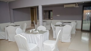 A room with multiple round tables, each covered with a white tablecloth and surrounded by white chairs. - Royal Shalom Lodge (Lusaka)